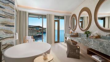 A modern bathroom with a large bathtub, a vanity with a marble countertop, and three wall-mounted mirrors.