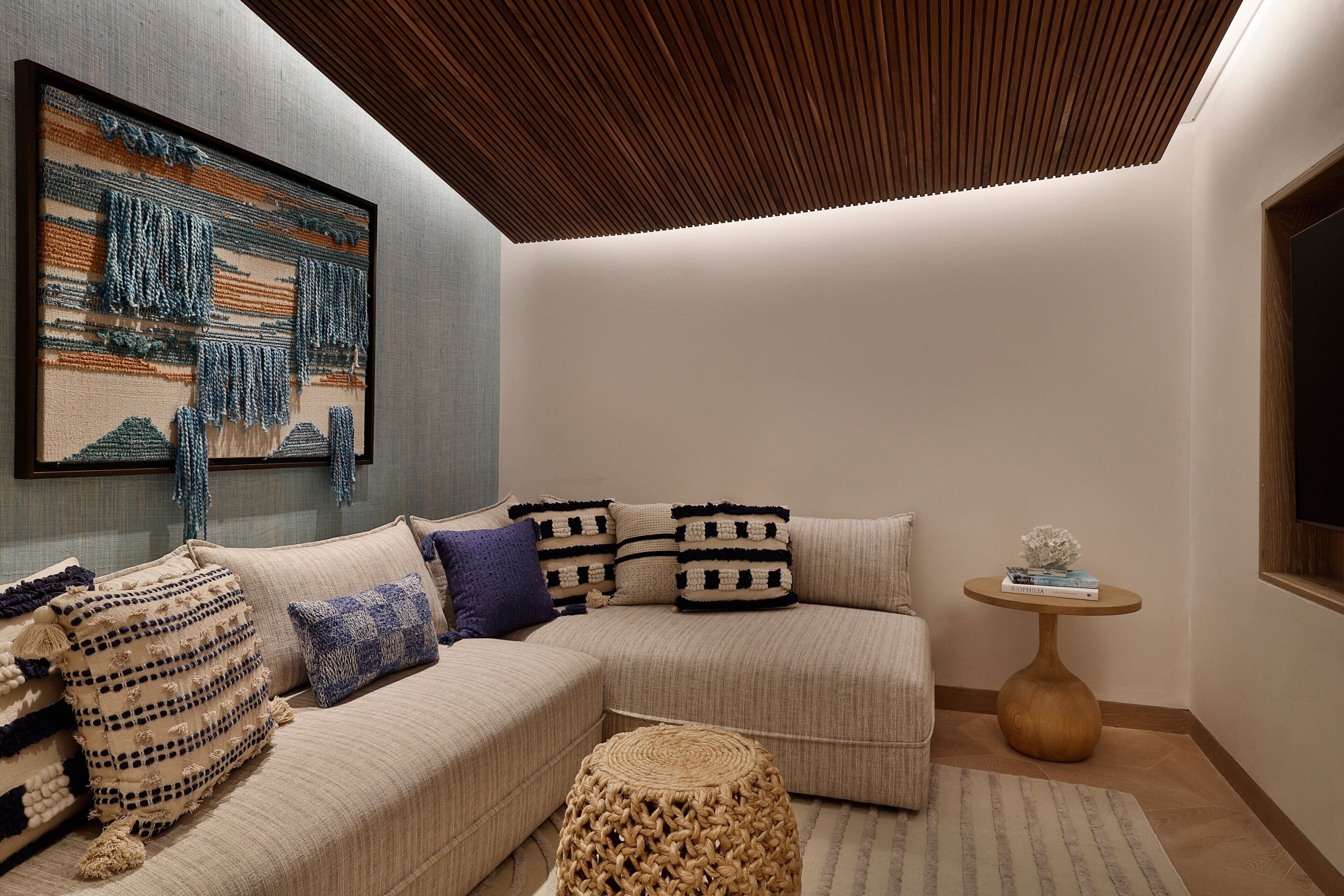 A modern living room with a sectional sofa, a woven coffee table, and a framed artwork on the wall.