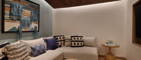 A modern living room with a sectional sofa, a woven coffee table, and a framed artwork on the wall.