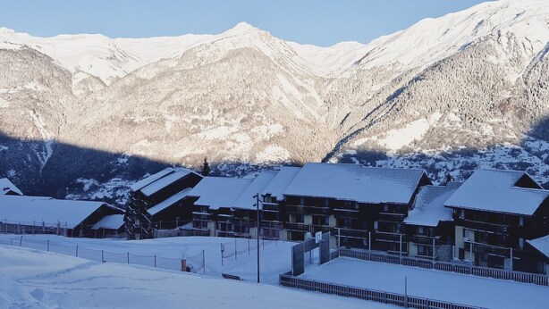 A snow-covered mountain resort with chalet-style buildings, a ski lift, and a clear view of the surrounding peaks. - Renovated studio at the foot of the slopes with balcony and equipped kitchen (La Plagne Montalbert)