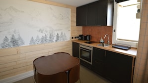 A compact kitchen with wooden cabinetry, a built-in oven, a sink, and a window with a view of the outdoors. - Renovated studio at the foot of the slopes with balcony and equipped kitchen (La Plagne Montalbert)