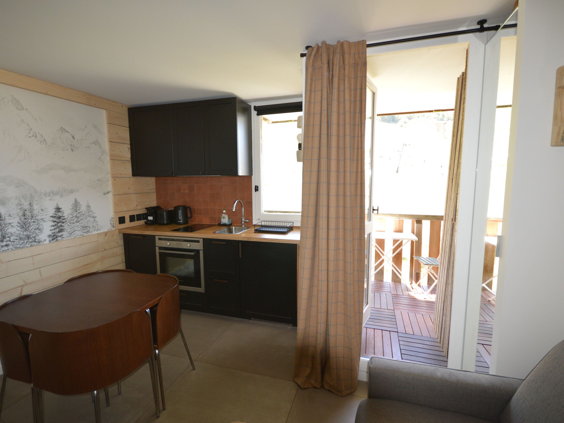 A compact kitchen with a dining area, a wooden table, and a sofa.