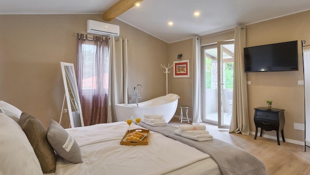 Una habitación de hotel con una cama grande, una bañera, un televisor y una bandeja para el desayuno.