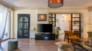 Una sala de estar con televisor, sofá, mesa de centro y un comedor con mesa y sillas.