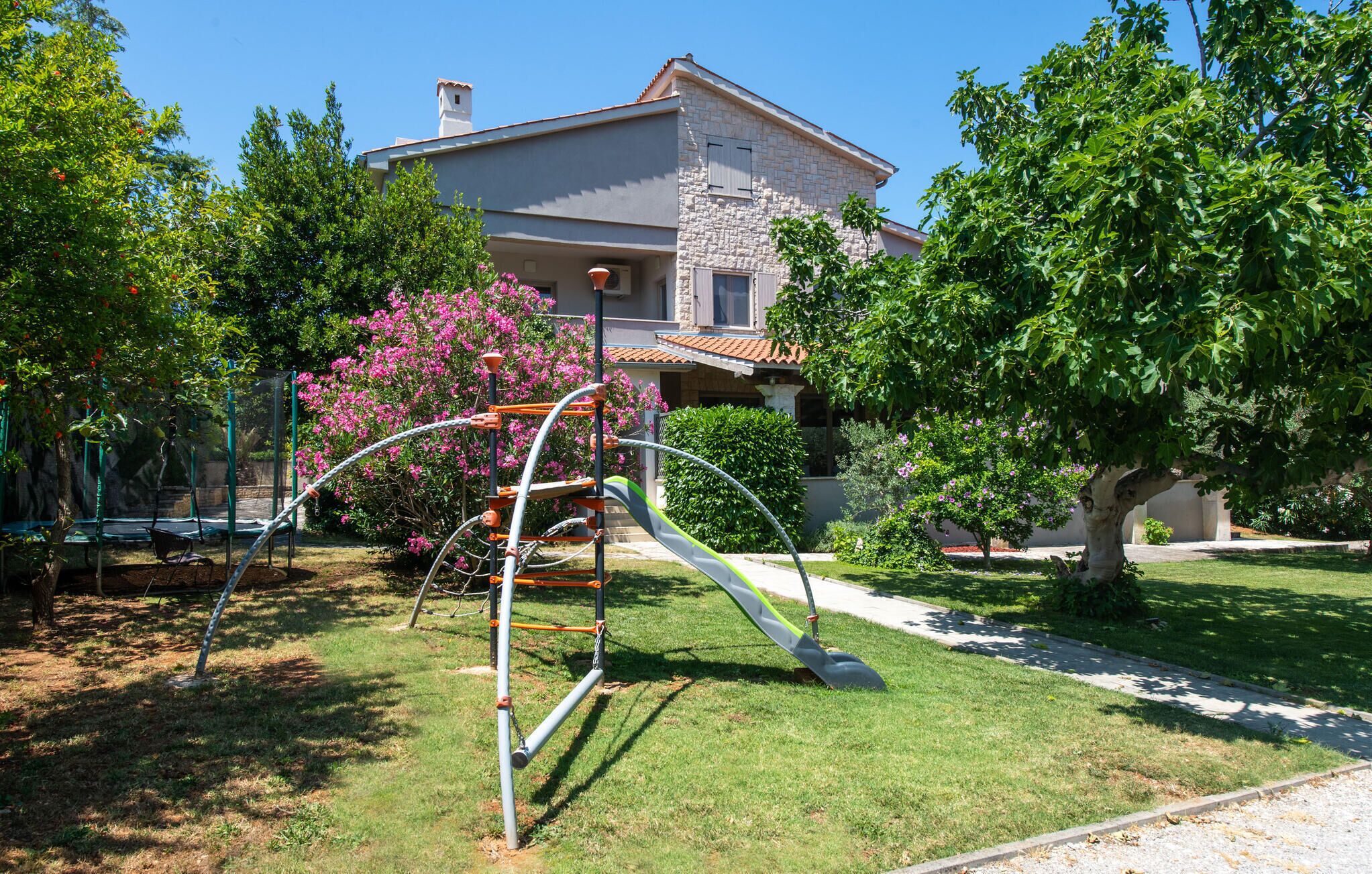 Zona residencial con una casa, un parque infantil y un césped bien cuidado.