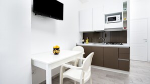 Une cuisine moderne avec des meubles blancs, un four à micro-ondes et un coin repas comprenant une table et des chaises blanches.
