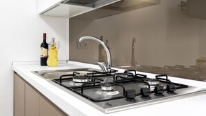 Une cuisine moderne équipée d’une cuisinière à gaz, d’un évier en acier inoxydable et de meubles blancs.