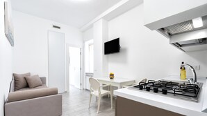 Une cuisine moderne équipée d’une cuisinière à gaz, de meubles blancs et d’un coin repas avec une table et des chaises.