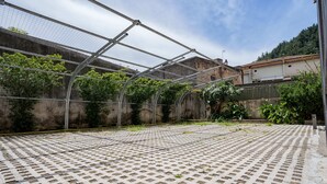 Une serre dotée d’une structure métallique et d’un plancher grillagé, entourée d’une clôture et de végétation.
