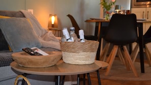A cozy living area with a sofa, a coffee table, a woven basket, and a dining table with chairs.