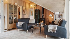 Een gezellige woonkamer met houten wanden, een open haard en twee banken.