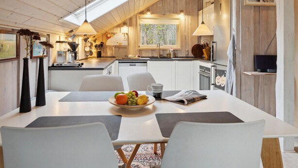 Een moderne keuken met witte kasten, een eettafel met stoelen en een groot raam.