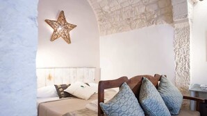 Ein gemütliches Zimmer mit einem Bett, einem Holzstuhl mit Kissen, einem dekorativen Stern an der Wand und einer Steinwand.