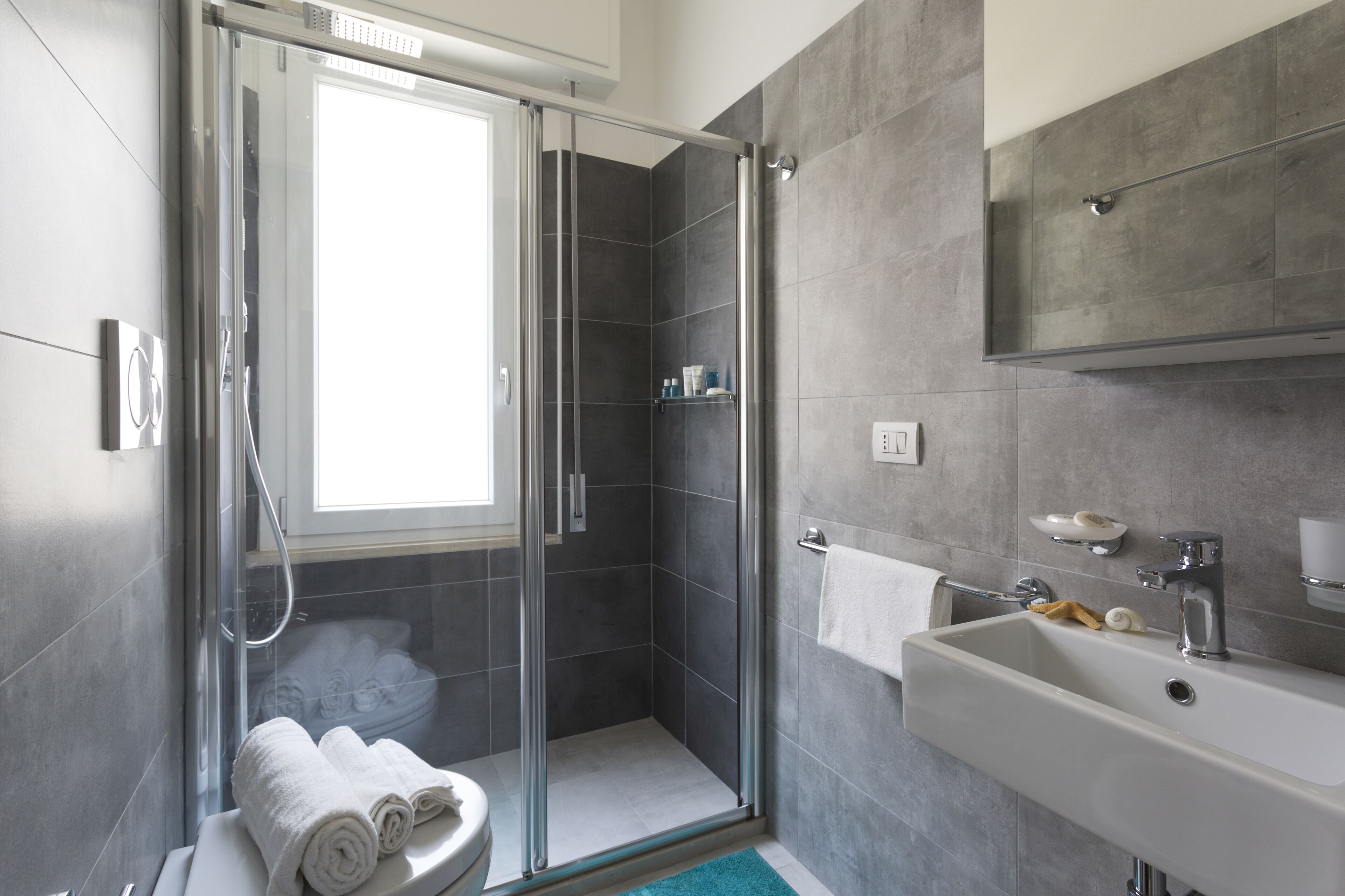 Un baño moderno con cabina de ducha de vidrio, un lavabo blanco y un espejo grande.