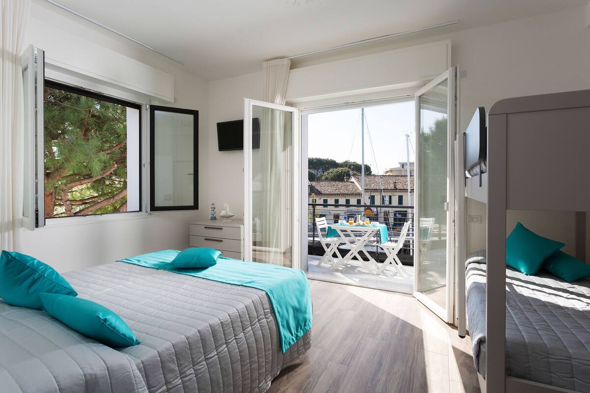 A bedroom with a bed, a TV, and a balcony with a table and chairs.