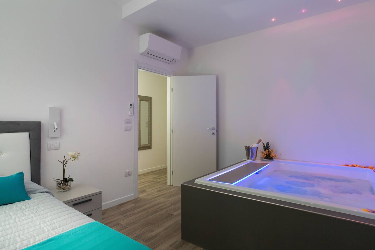 A modern bedroom with a bed, bedside table, and a heated floor bath.
