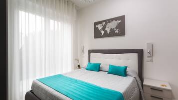 A modern bedroom with a large bed, a world map on the wall, and a bedside table with a lamp.