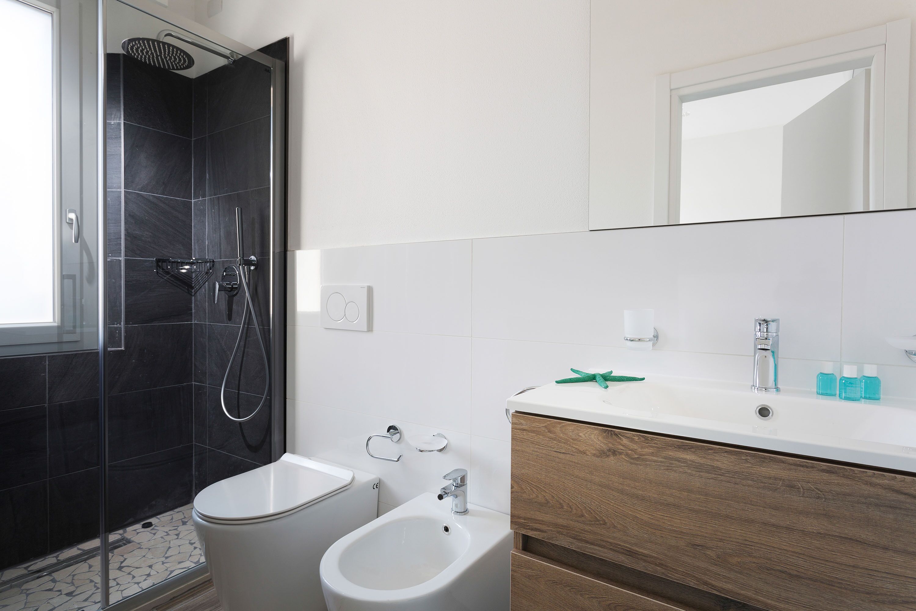 A modern bathroom with a shower, toilet, bidet, and vanity.