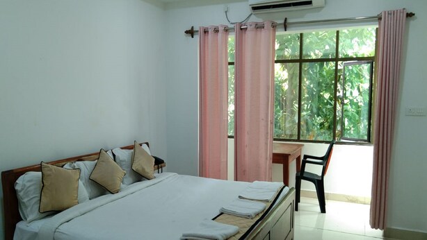 A bedroom with a bed, a desk, and a chair. - Finix Residency (Puducherry)