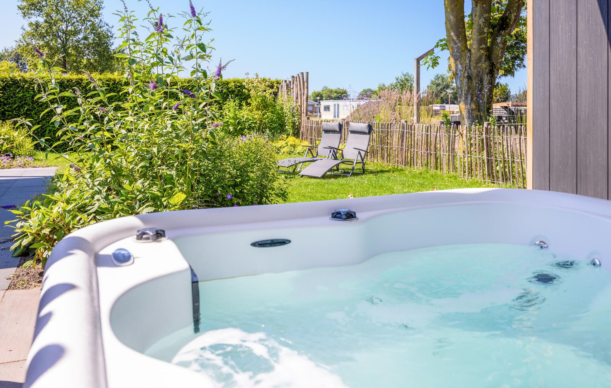 A hot tub with a clear view of the surrounding garden and a wooden fence.