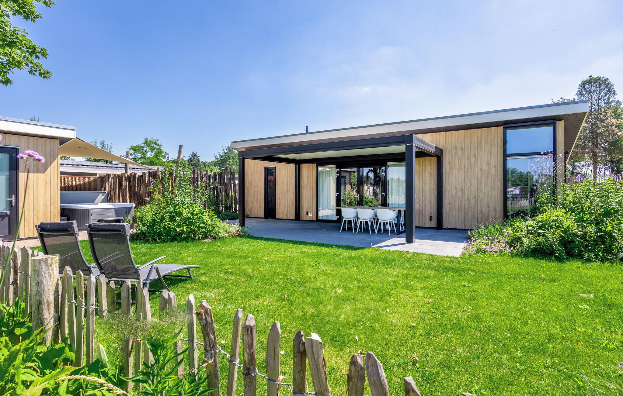 A modern house with a covered patio, a barbecue area, and a well-maintained lawn.