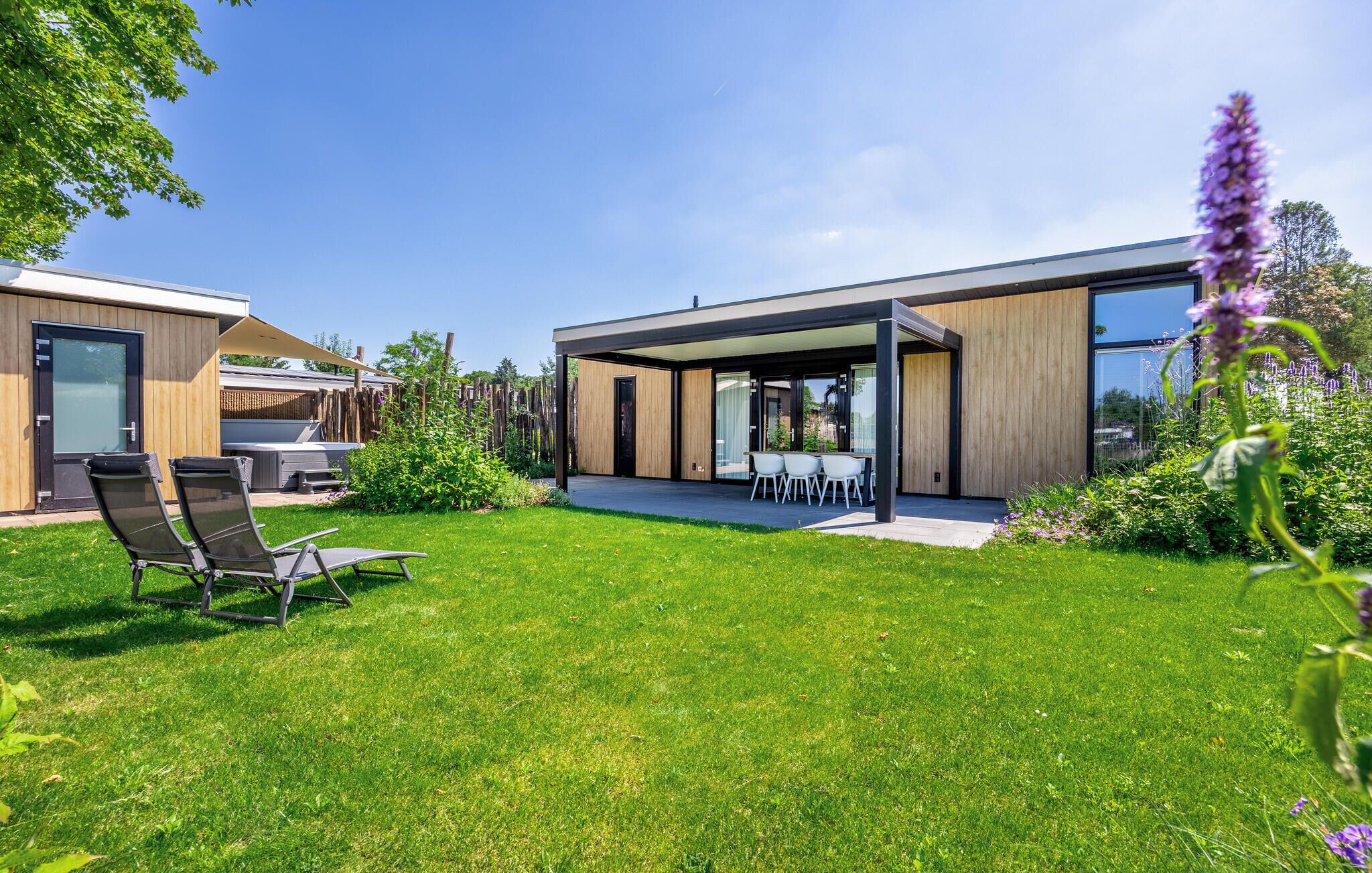 A modern house with a covered patio, a lawn, and a barbecue area.