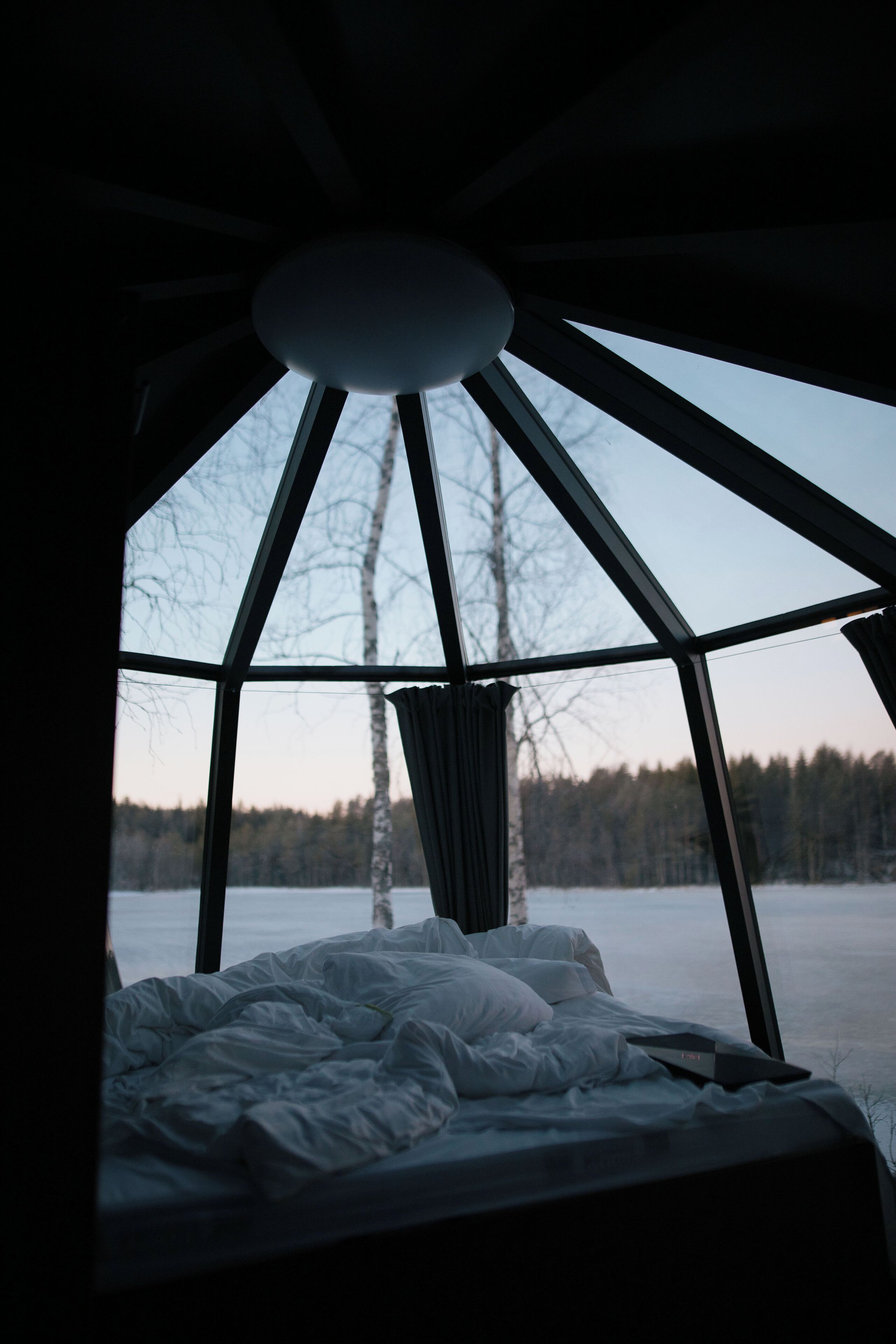 A bed with a view of a snowy landscape through a large window.