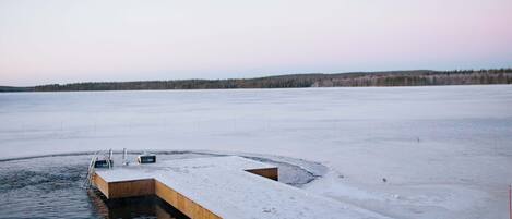 A wooden dock extending into a frozen lake with a clear sky.