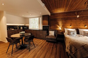 Habitación compacta con cocina, una mesa de comedor con sillas, un sofá y una cama con ropa de cama estampada.