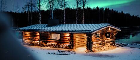 A log cabin with a metal roof, wooden walls, and a window.