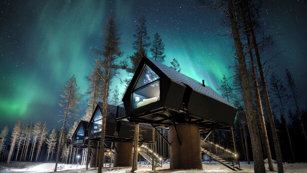 A snow-covered outdoor area with a modern building structure featuring large windows and a staircase leading up to a platform. - Aito  Igloo & Spa Resort (Rovaniemi)