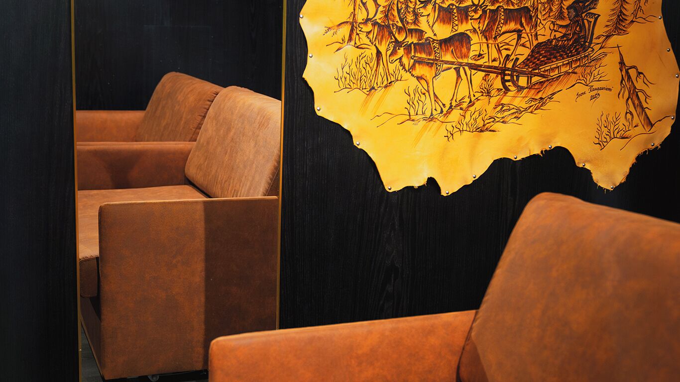 A room with a dark wall and a large, yellow, tribal-style artwork depicting a scene with animals and a cart.
