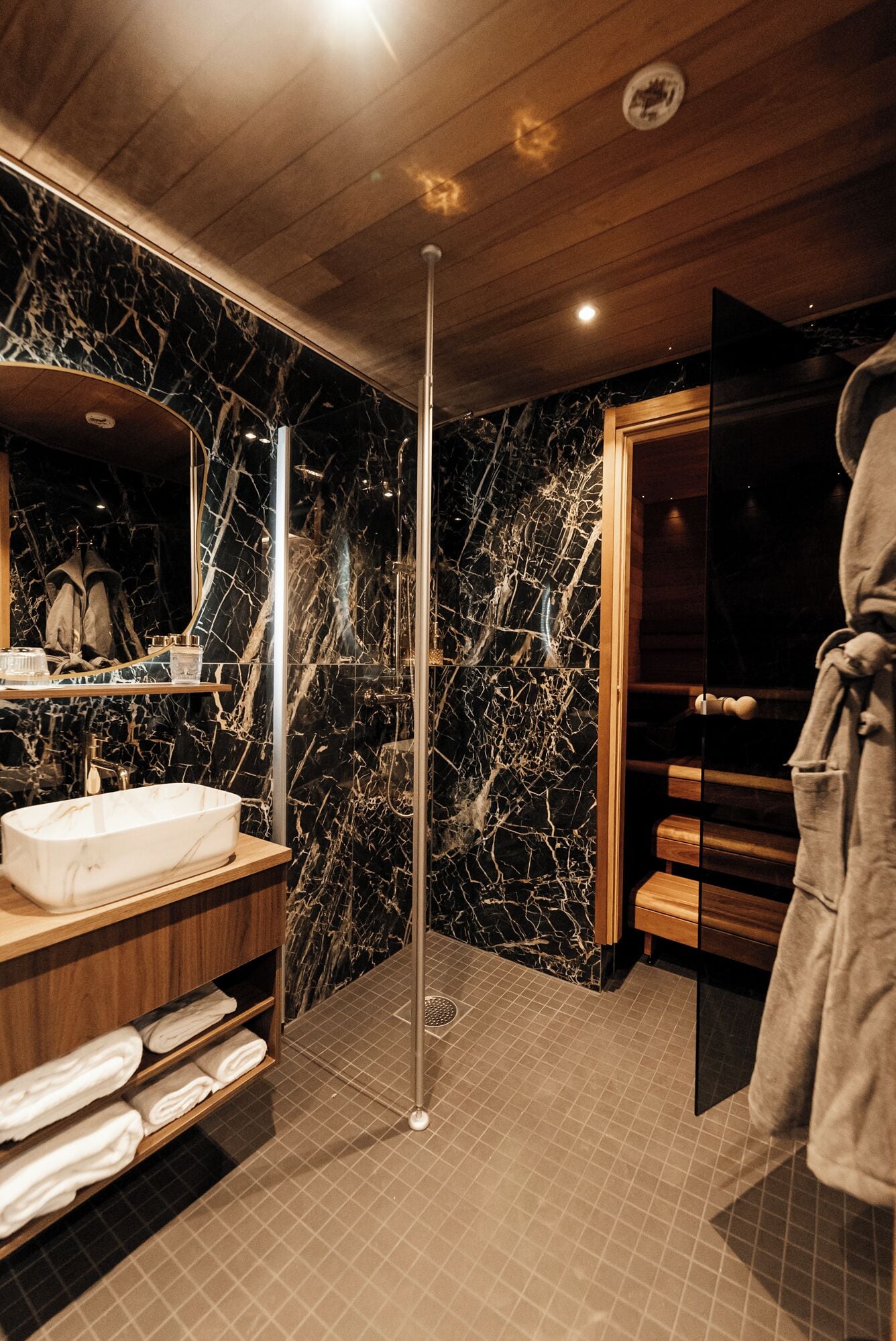 Une salle de bain moderne avec un meuble-lavabo en marbre, une cabine de douche en verre et un escalier en bois.