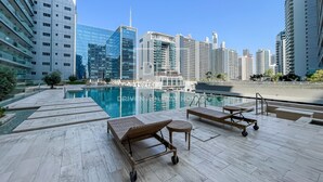 A rooftop pool area with lounge chairs and a pool, surrounded by high-rise buildings. - Damac Majestine (Dubai)