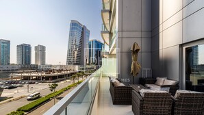 A modern building with a balcony featuring wicker furniture and a view of a cityscape with tall buildings. - Damac Majestine (Dubai)