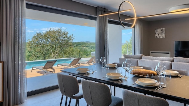 Un comedor moderno con vista a la piscina, un sofá y un televisor.