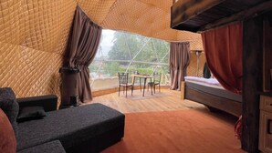 A cozy room with a large window, a bed, a table with chairs, and a sofa. - Lake View Dome Sleeps 6 -hot tub -fireplace (Horni Podluzi)