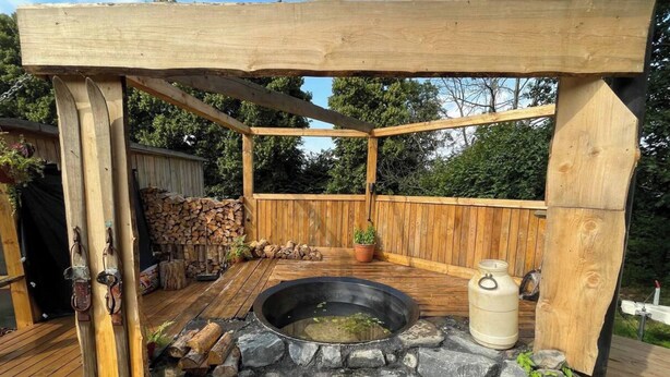 A wooden deck with a stone fire pit, a wooden pergola, and a wooden fence. - Lake View Dome Sleeps 6 -hot tub -fireplace (Horni Podluzi)