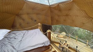 A cozy, tent-like interior with a bed, a wooden deck, and a view of the outdoors. - Lake View Dome Sleeps 6 -hot tub -fireplace (Horni Podluzi)