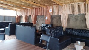An indoor seating area with wooden panel walls, black leather sofas, and a wooden table. - WHITE HOUSE LOUNGE & GUEST HOUSE (Eldoret)