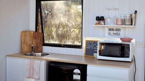 Une cuisine avec une fenêtre, un évier, un four à micro-ondes et un panneau d’avertissement.