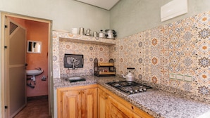Une cuisine avec des meubles en bois, une cuisinière à gaz et un dosseret carrelé.