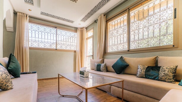 Un salon comprenant un canapé, une table basse et une fenêtre ornée de barreaux en fer décoratifs.