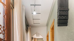 Un couloir doté d’un plancher en bois, d’une porte en bois et offrant une vue sur l’extérieur.