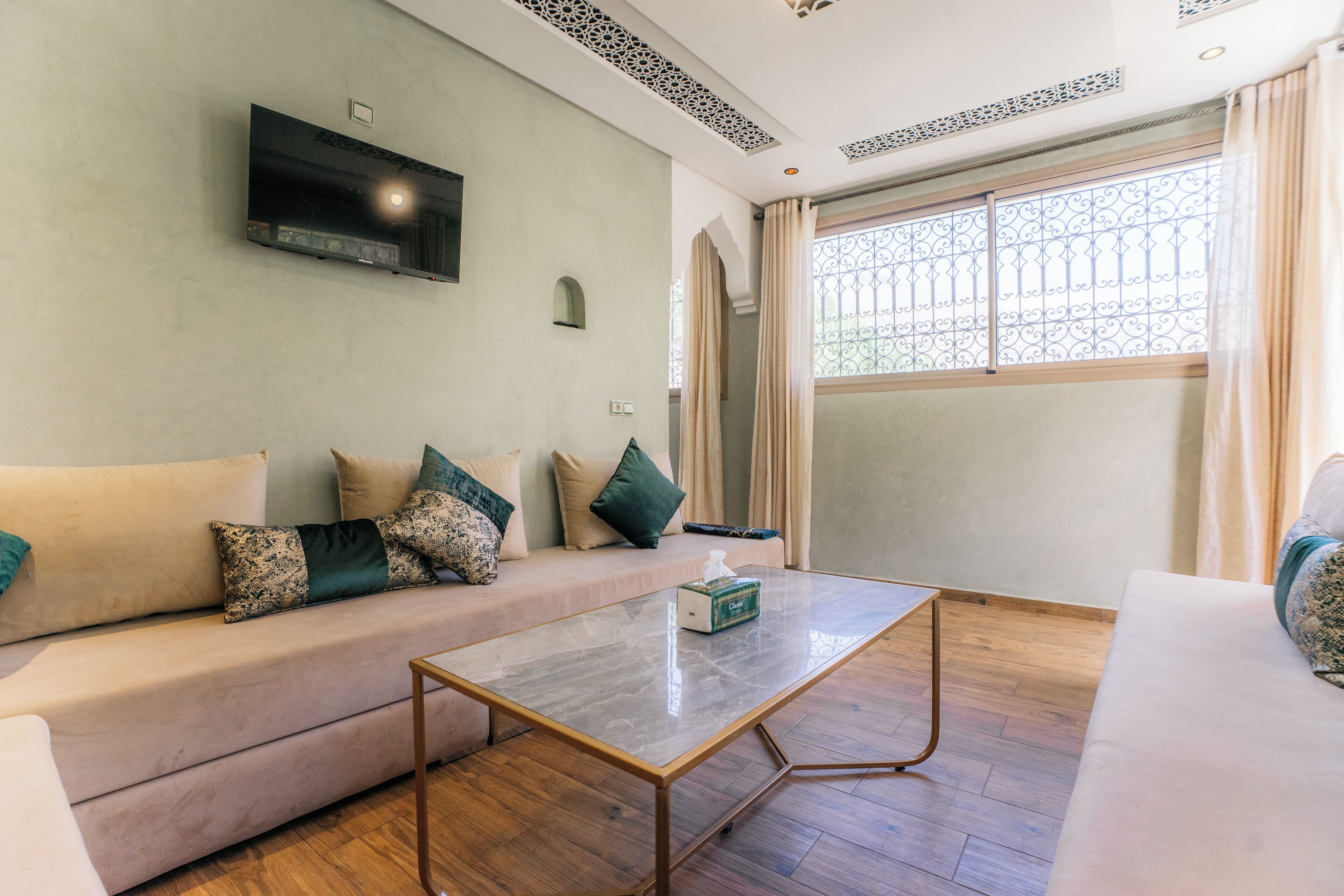 Ein Wohnzimmer mit einer Couch, einem Couchtisch und einem an der Wand montierten Fernseher.