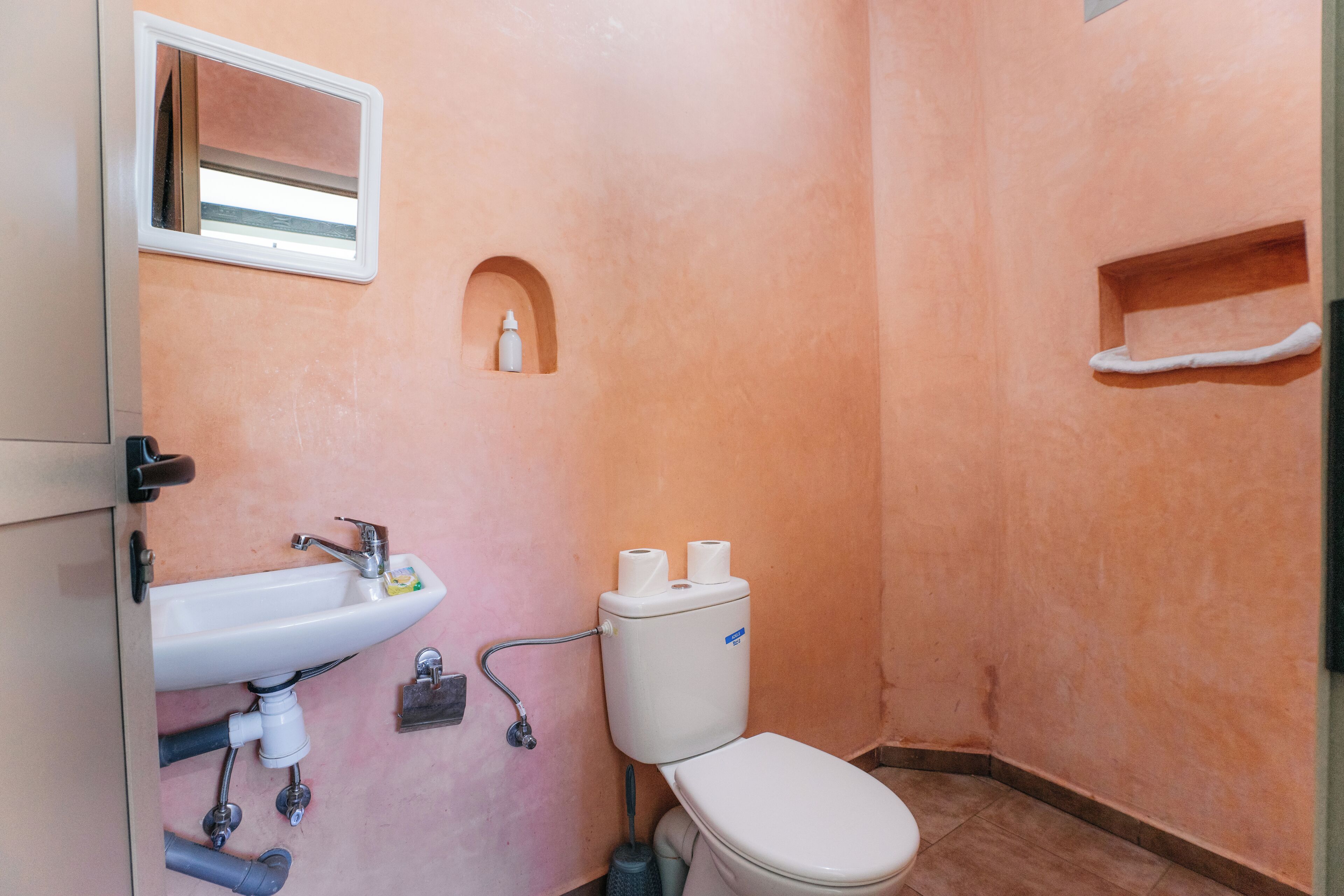 Un bagno con lavandino, WC e una piccola finestra.