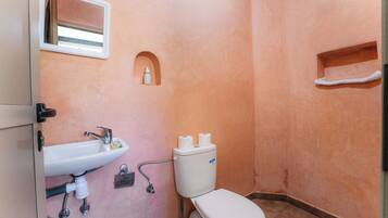 Un bagno con lavandino, WC e una piccola finestra.