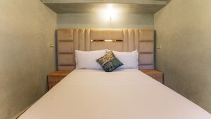 Un lit avec une tête de lit, deux tables de chevet et un luminaire placé au-dessus de la tête de lit.