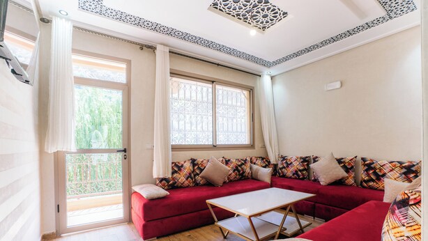 Una habitación con un sofá rojo, una mesita y una ventana con vistas a zonas verdes.