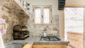 Una cocina con encimera de granito, estufa a gas, pileta y ventana con marco de madera.